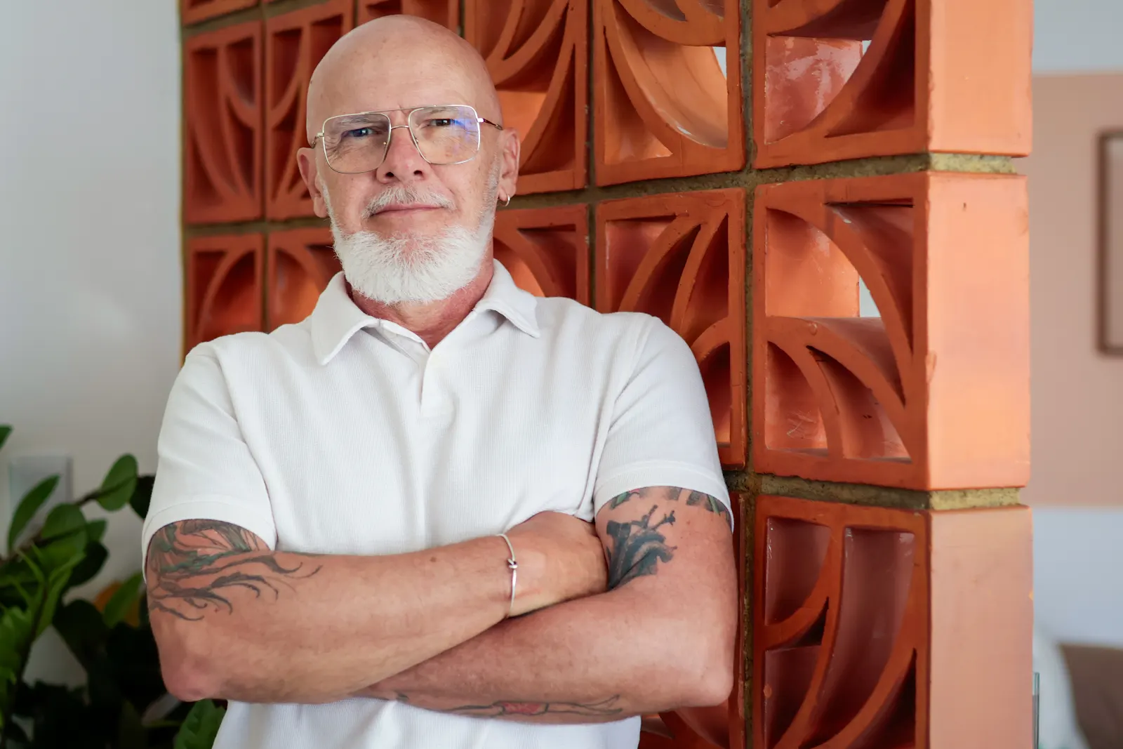Luciano Meira, de camisa branca, diante de uma parede de cobogós em terracota.